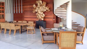 Un interior moderno con una zona de comedor, una gran escultura abstracta y una escalera de caracol.