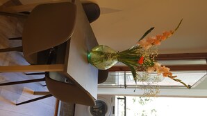Ein Esstisch mit Stühlen, eine Vase mit Blumen und im Hintergrund eine Waschmaschine.