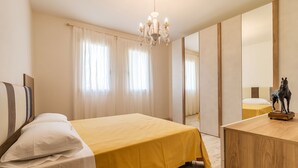 A hotel room with a bed, a wooden dresser, a chandelier, and a horse statue.