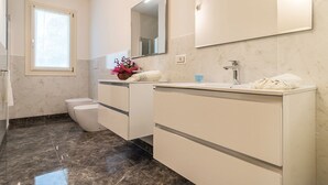 A modern bathroom with a toilet, a sink, and a mirror.