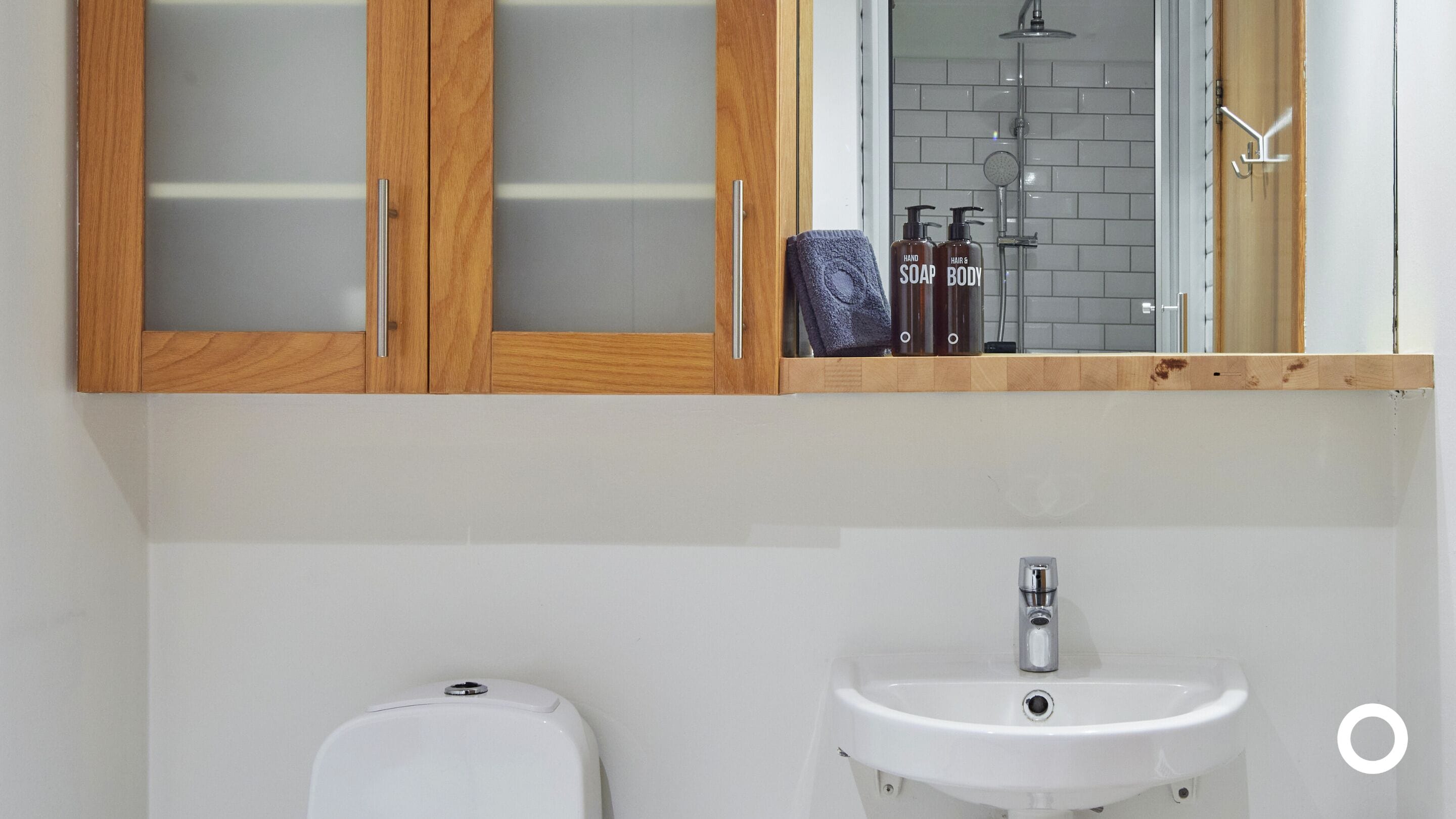 Een badkamer met een houten kastje, een witte wastafel en een toilet.