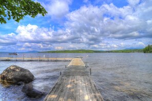 A wooden pier extending into a lake with a cloudy sky above.
