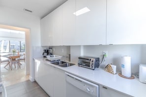 Una cocina moderna con armarios blancos, lavavajillas, tostadora y cafetera.