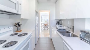 Une cuisine moderne avec des meubles blancs, une cuisinière, un four à micro-ondes et un évier.