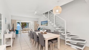 A modern interior with a dining area, a staircase, and a view to the outside. - 2 Bedroom Oceanfront Penthouse Beach Club (Palm Cove)