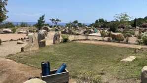 Un jardín con rocas grandes, una mesa de picnic y un área de juegos pequeña.