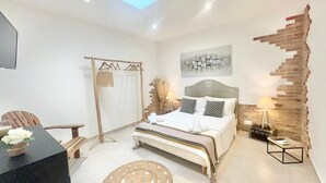 Un dormitorio moderno con cama, escritorio, silla, perchero y un diseño de pared de ladrillo único.