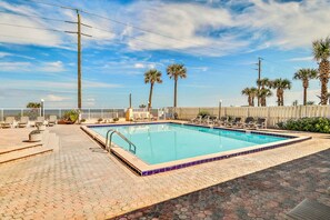 A rectangular pool with a tiled edge, surrounded by lounge chairs and palm trees. - Direct Beach Views - Sleeps 4, Corner Unit Tennis - Pool (Flagler Beach)