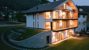 Una casa moderna de dos pisos con base de piedra, amplios ventanales y un interior luminoso.