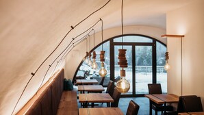Un interior acogedor y moderno con mesas y sillas de madera, ventanas amplias y lámparas colgantes originales.