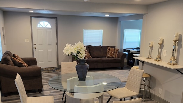 A modern living room with a glass-top dining table, two sofas, and a coffee table. - Spacious Cheerful 1-Bedroom Residential Home (Tulsa)