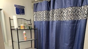 A bathroom with a toilet, a sink, a mirror, a shelf with toiletries, and a blue shower curtain. - Spacious Cheerful 1-Bedroom Residential Home (Tulsa)