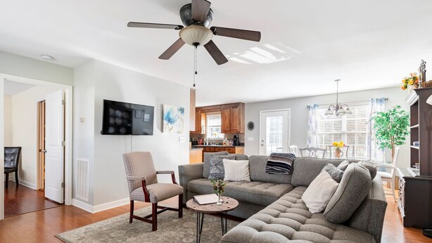 Un salon moderne avec un canapé d’angle, une table basse, un téléviseur et un ventilateur de plafond.