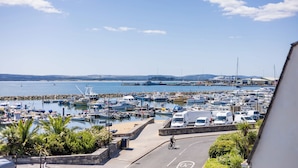 A marina with boats, a cyclist, and parked vehicles. - Candle Island View - Harbour Views (Poole)