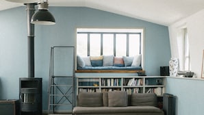 Een gezellige kamer met een houten vloer, een bank, een boekenkast en een zwarte verwarming.