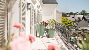 Een balkon met potplanten en een metalen stoel.