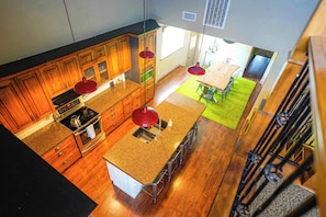 A kitchen with wooden cabinets, granite countertops, and a central island with stools.