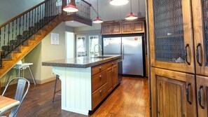A kitchen with wooden cabinets, a stainless steel refrigerator, and a granite countertop island.