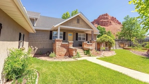 A single-story house with a front porch, stone pillars, and a well-maintained lawn.