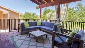 A covered outdoor seating area with a wooden bench, a sofa, and a table.