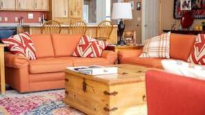 Una sala de estar con un sofá, una mesa de centro de madera y una alfombra estampada.