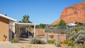 A fenced outdoor area with a pergola, a wooden fence, and a mountain backdrop. - Vacation Home w/red rock views, Near Zion & Bryce (Kanab)