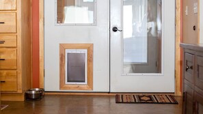 A kitchen with wooden cabinets, a pet door, and a pet bowl on the floor.