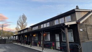 A two-story building with a covered patio area, featuring outdoor seating and a small garden. - CORRAL VILLAS<br>Deluxe studios in the north entrance to Yellowstone (Gardiner)