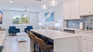 A modern kitchen with a large island, white cabinetry, and a blue backsplash.