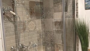 Cabina doccia in vetro con soffione e doccetta a mano.