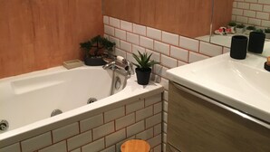 Un bagno con una vasca, un lavandino, uno specchio e un cestino.