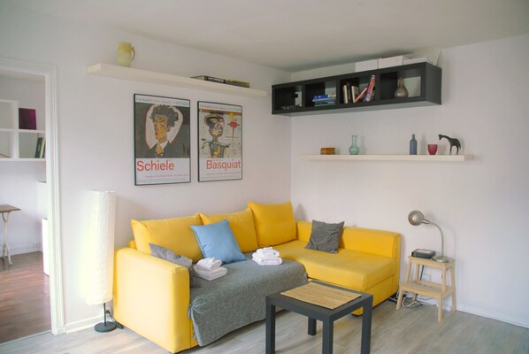 A modern living room with a yellow sofa, a coffee table, and a bookshelf.