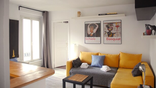A living room with a yellow sofa, a small table, and two posters on the wall. - ★ Zen cocoon, calm & bright in Belleville ★ (Paris)