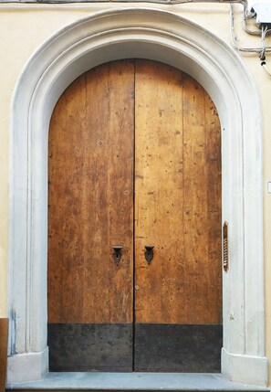 Eine große Holztür mit Metallbeschlägen, eingebettet in einen weißen Bogen.