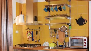 Una cocina con electrodomésticos de acero inoxidable, un tostador y un tendedero con utensilios de cocina.