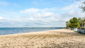 A beach with a sandy shore, a body of water, and a distant shoreline with buildings.