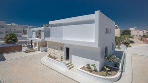 A modern two-story house with a flat roof, large windows, and a stone foundation. - Ayia Napa Kube Villa KB4 -  a villa that sleeps 12 guests  in 5 bedrooms (Ayia Napa)