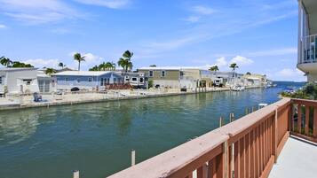 A marina with RVs docked along a calm waterway, surrounded by palm trees and a clear sky.