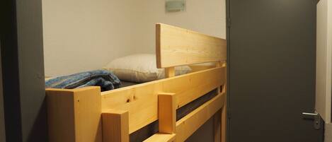 A single bed with a wooden frame, a white pillow, and a blue blanket.