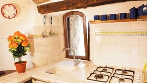A kitchen with a sink, stove, and a clock on the wall. - La Casetta in the historic center of Bomarzo (Bomarzo)