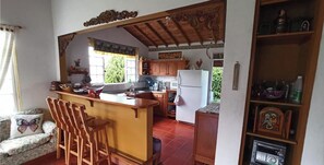 A kitchen with wooden cabinets, a white refrigerator, a sink, and a bar area with stools.