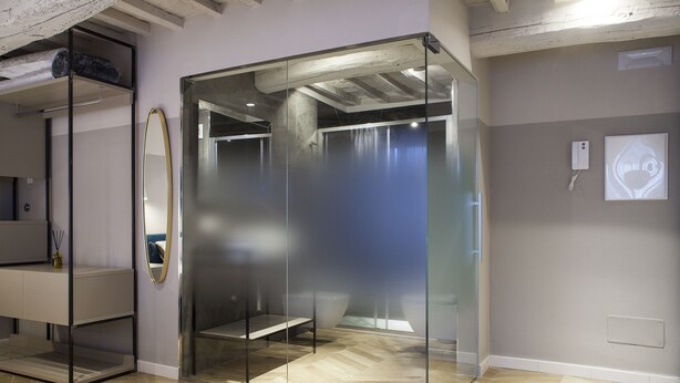 A modern bathroom with a glass enclosure, a wooden floor, and a shower area.