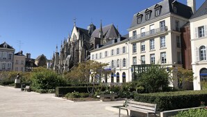 A historic building with Gothic architecture, a paved plaza, and a bench. - Charmant Zola (Troyes)