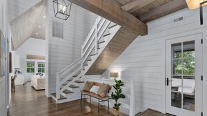 Un interior espacioso con una escalera de madera, un banco acolchado y una planta en maceta.