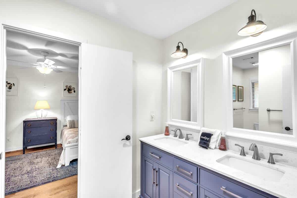 A bathroom with a double sink, vanity, and a ceiling fan.