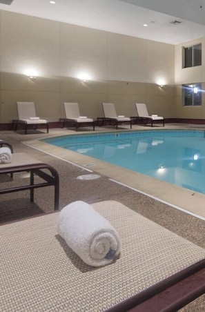 A swimming pool with lounge chairs and towels.