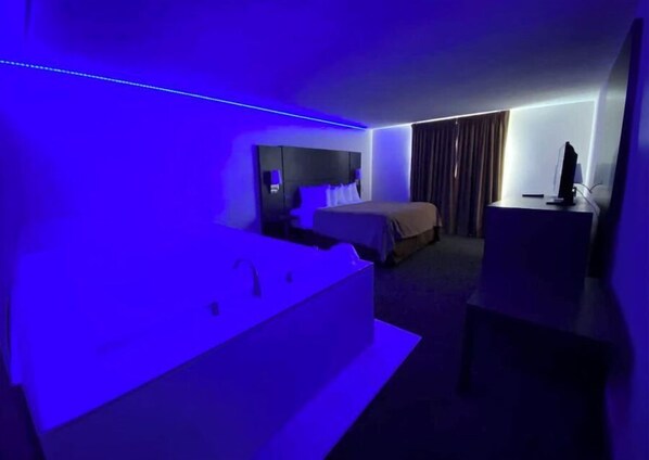 A hotel room with a bed, a desk, and a bathroom.