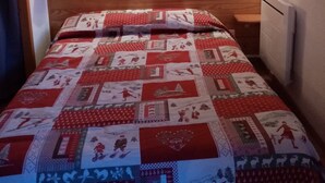 Habitación con paneles de madera y una cama con colcha roja y blanca.
