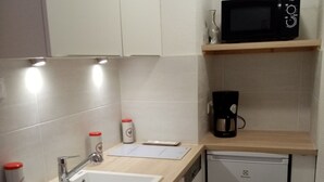 Una cocina compacta equipada con lavaplatos, microondas, cafetera y pileta.