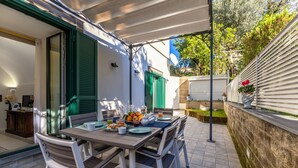 An outdoor dining area with a table set for breakfast, including plates, cups, and a fruit bowl. - SMALL COURT MAISON (Piano di Sorrento)